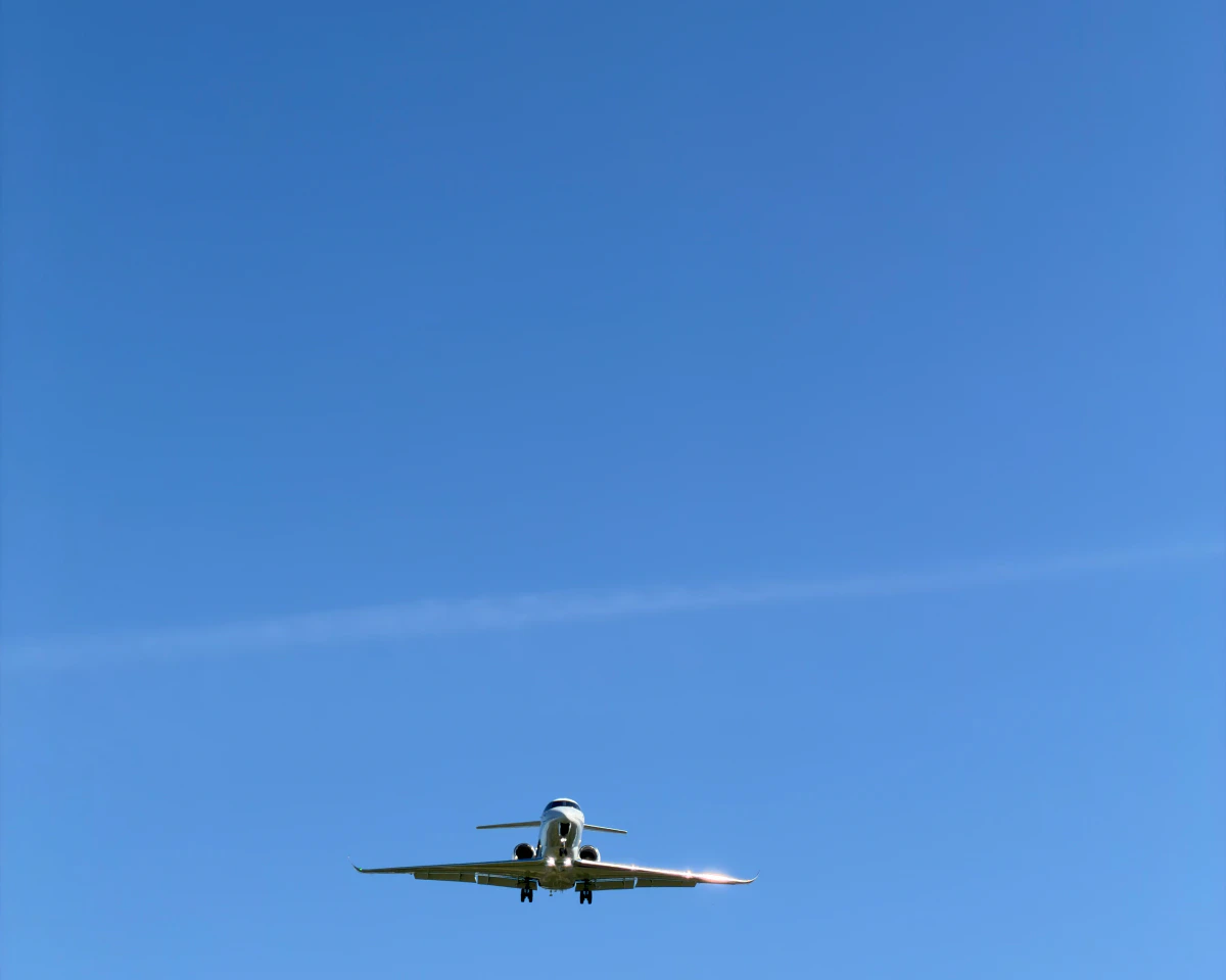 A business jet on approach, far away in a clear blue sky