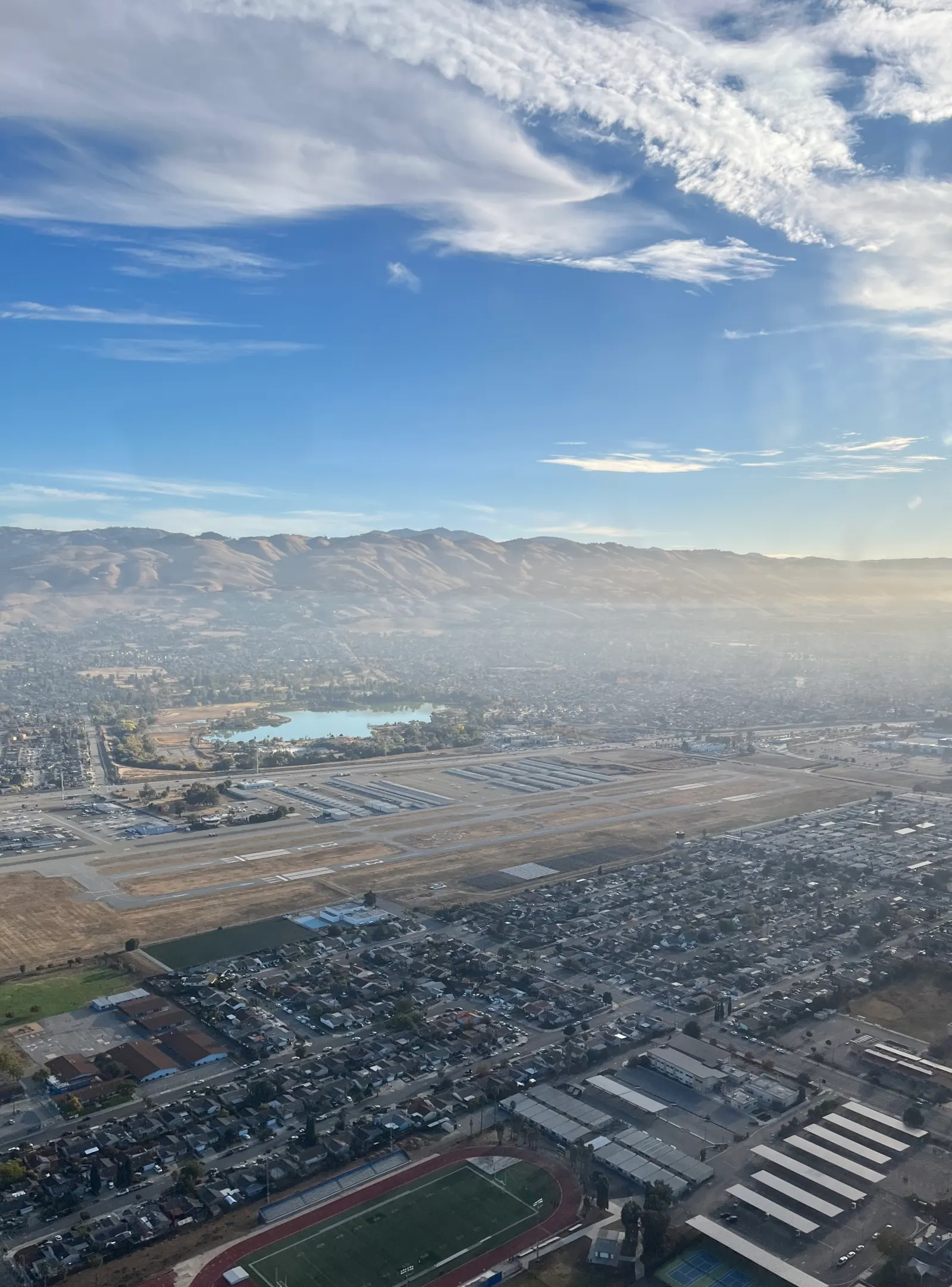 A general aviation airfield seen from the air, with hills behind