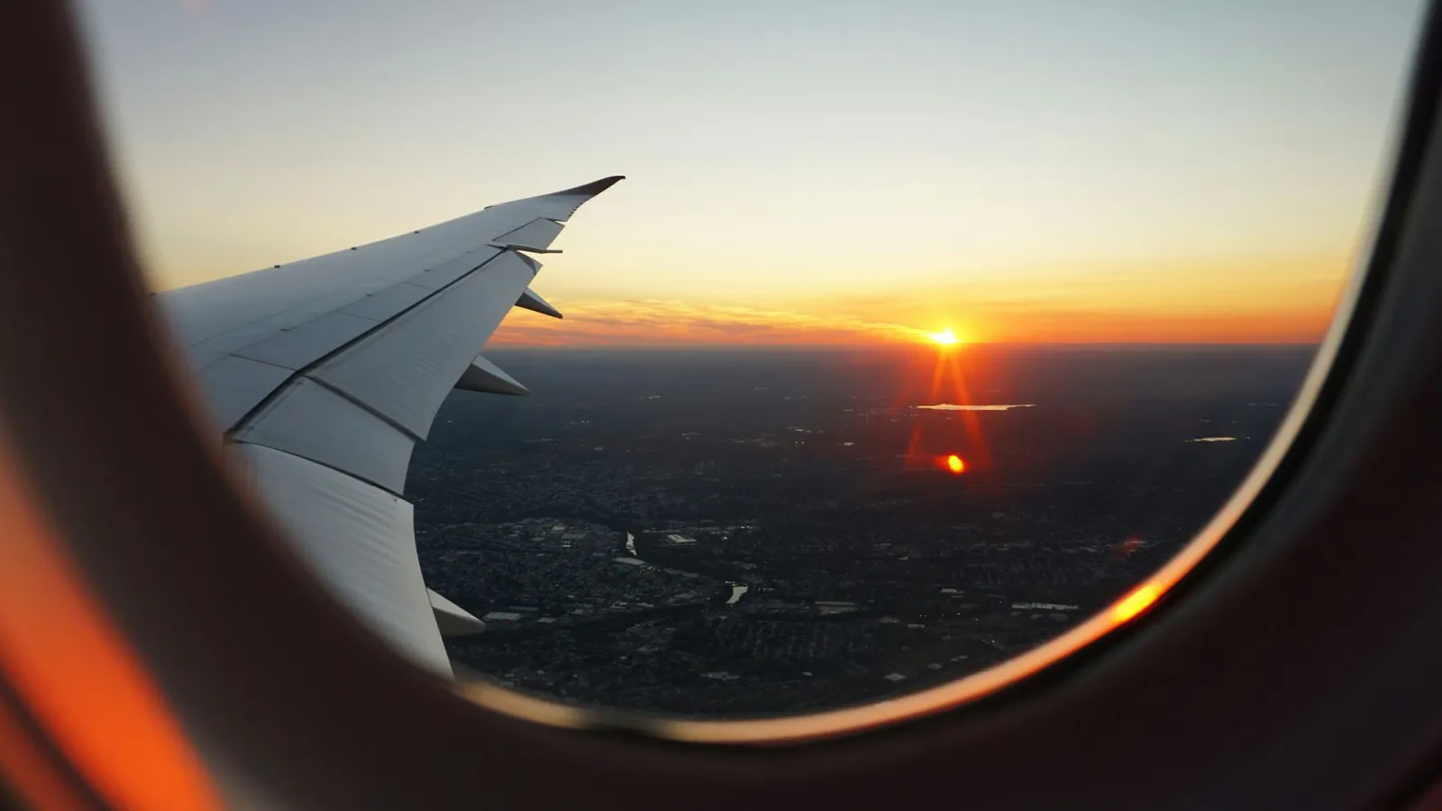 An aircraft wing at sunset, seen through the cabin window